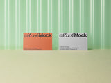 Orange and white business cards mockup on a green corrugated plastic background.