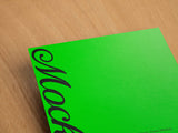 Green poster/letterhead mockup on a wooden background top view.