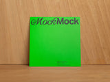 Green square card mockup on a wooden background.