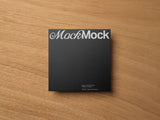 Black square card mockup on a wooden background top view.
